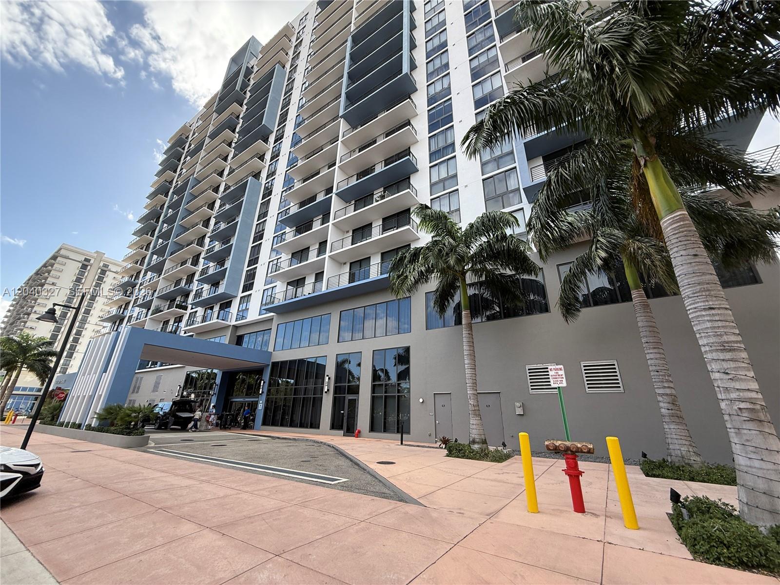 A tall modern apartment building features balconies, a covered entrance, and palm trees in front — 5350 NW 84th Ave # 1001, Doral FL 33166, DORAL, FL