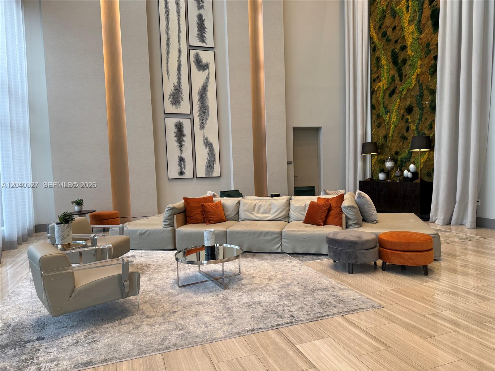 A modern, high-ceilinged lounge features a large sectional sofa, accent chairs, and a moss wall — 5350 NW 84th Ave # 1001, Doral FL 33166, DORAL, FL