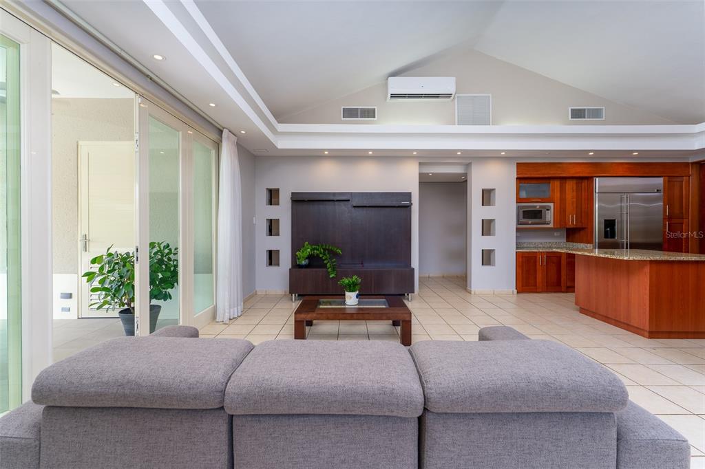 A living room with a gray sofa, dark wood media console, and an open kitchen — 291 SABANERA DE DORADO, DORADO, PR