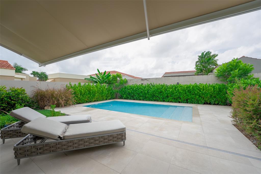 A rectangular swimming pool sits on a tiled patio next to two lounge chairs — 291 SABANERA DE DORADO, DORADO, PR