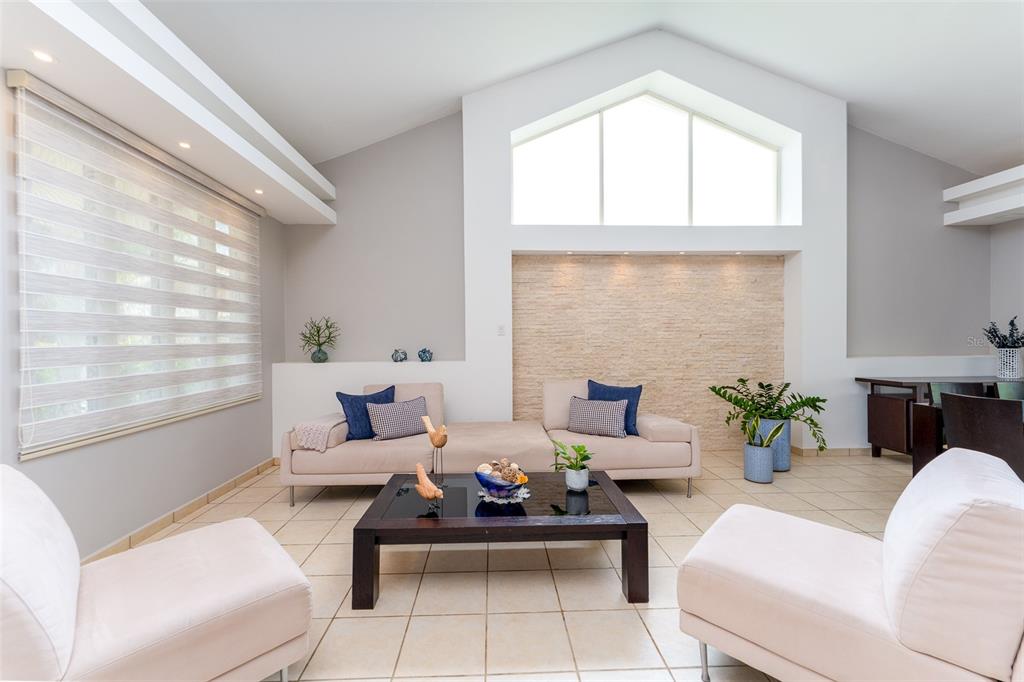 A living room features a vaulted ceiling, a stone accent wall, and light-colored tile flooring — 291 SABANERA DE DORADO, DORADO, PR