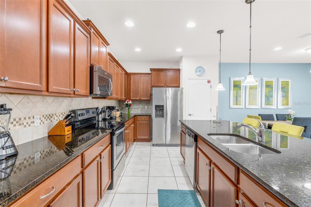A kitchen with wood cabinets, dark granite countertops, stainless steel appliances, and tile flooring — 1987 MAJORCA DRIVE, KISSIMMEE, FL