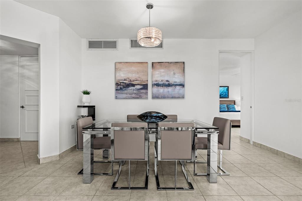 A dining room features a glass-topped table with six chairs under a modern pendant light — 100 OCEAN DRIVE UNIT 144, HUMACAO, PR
