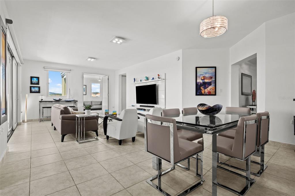 An open-concept living and dining area features tile flooring, modern furniture, and a glass table — 100 OCEAN DRIVE UNIT 144, HUMACAO, PR