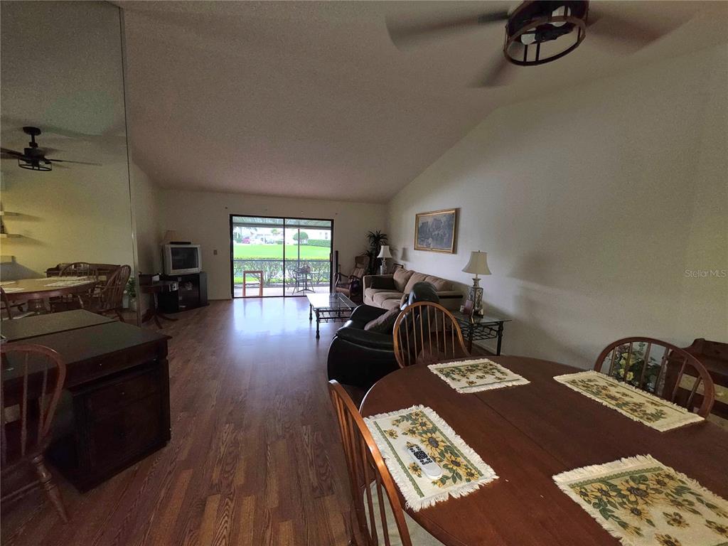 A living and dining area features wood-look flooring, a sliding glass door, and a ceiling fan — 18427 AINTREE COURT, TAMPA, FL