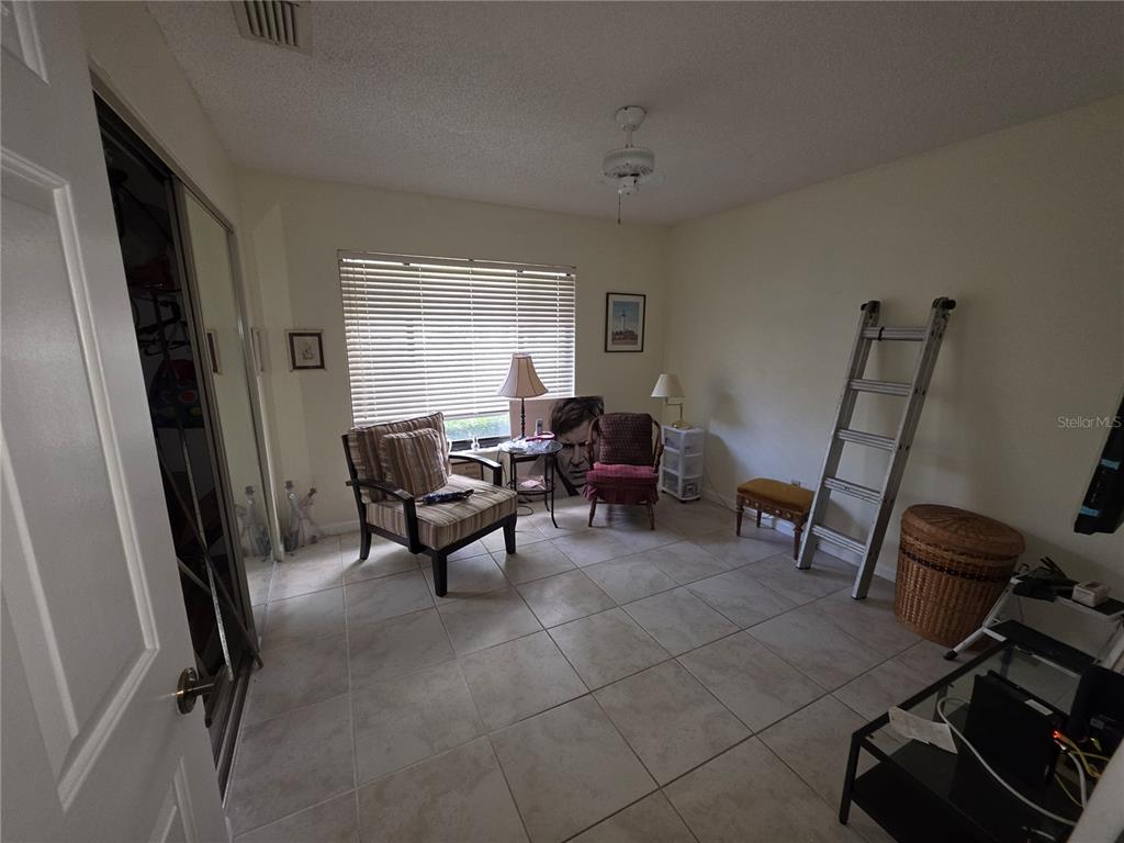 A room with tiled flooring, a window with blinds, two chairs, and a metal ladder — 18427 AINTREE COURT, TAMPA, FL