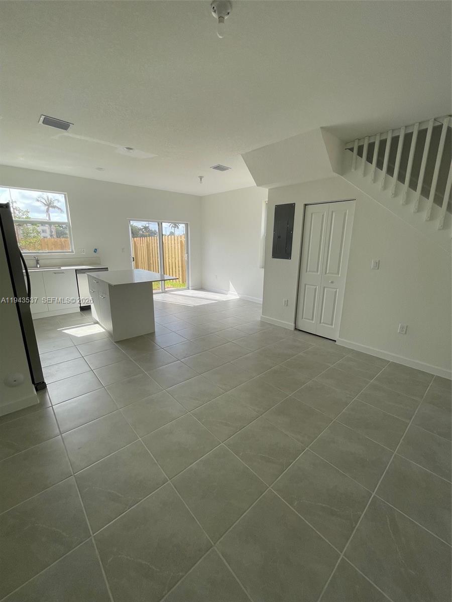 An open-concept kitchen and living area features white cabinetry, a center island, and tile flooring — 12075 NW 24th Ct, Miami FL 33167, MIAMI, FL
