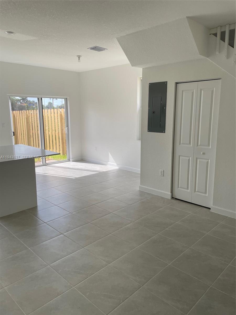 A room with light-colored tile flooring, a sliding glass door, and a white closet door — 12075 NW 24th Ct, Miami FL 33167, MIAMI, FL