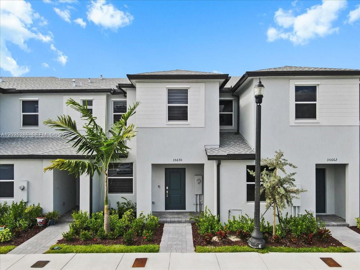 A two-story townhouse exterior features light gray stucco walls, dark window frames, and a palm tree — 35670 SW 178 Ct, Miami FL 33034, MIAMI, FL