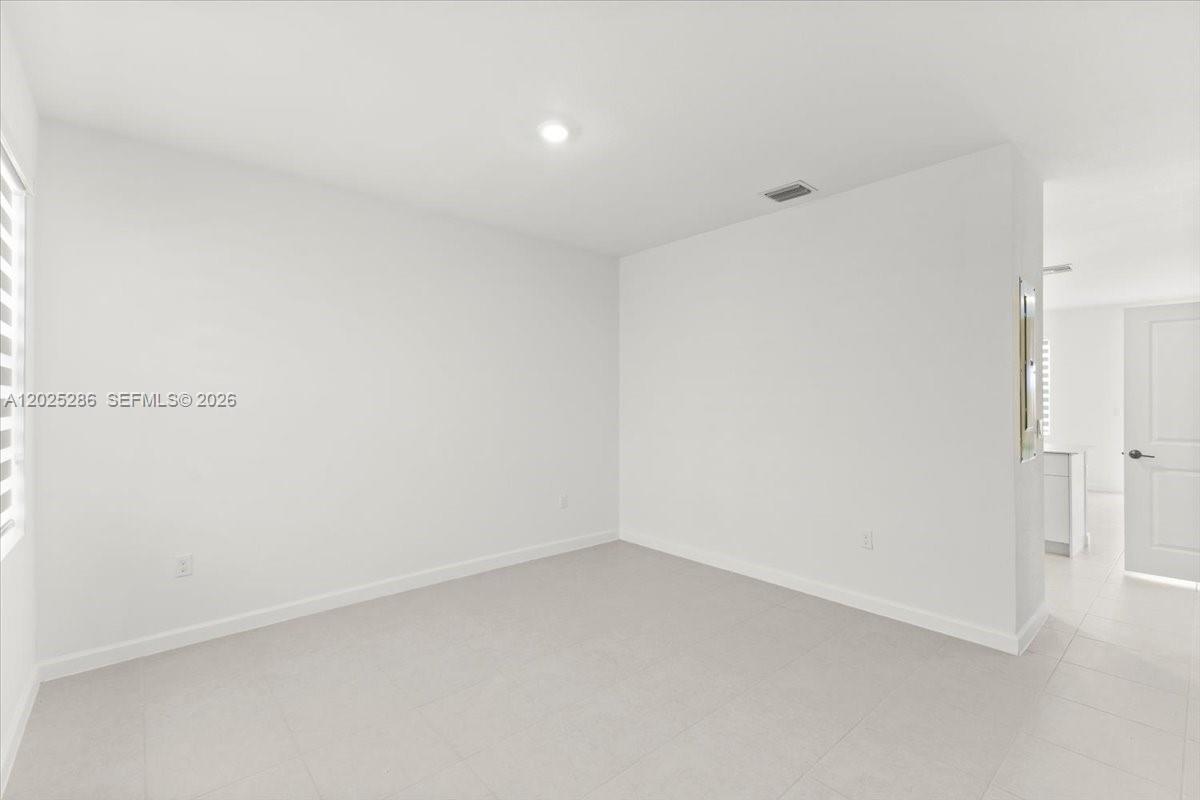 An empty room features white walls, a recessed ceiling light, and light-colored tile flooring — 35670 SW 178 Ct, Miami FL 33034, MIAMI, FL