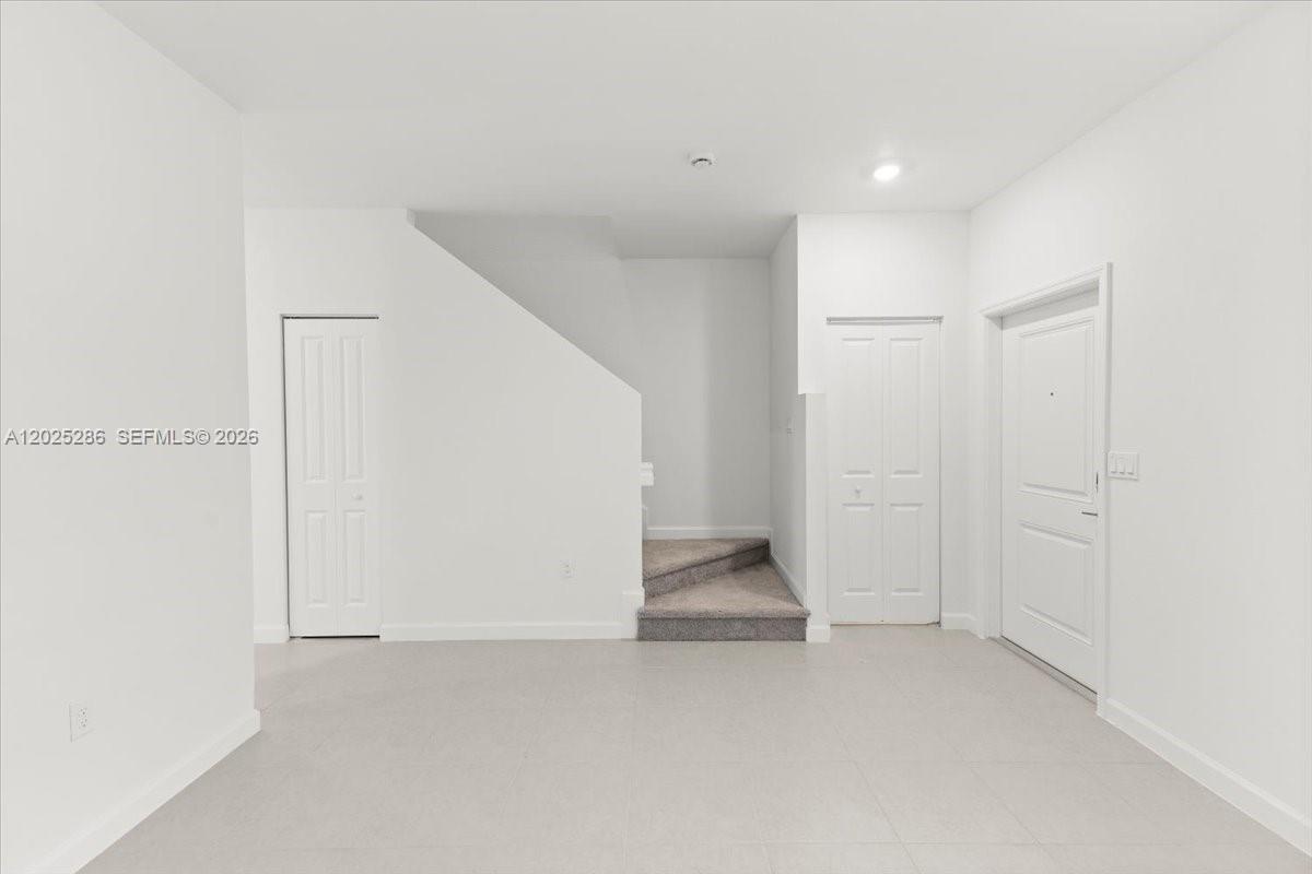 An interior view shows a room with light-colored tile flooring, white walls, and carpeted stairs — 35670 SW 178 Ct, Miami FL 33034, MIAMI, FL
