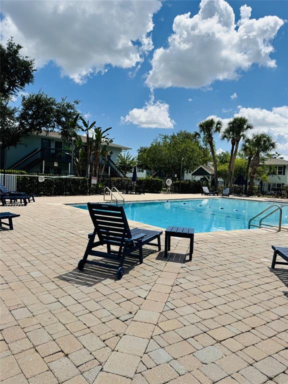A swimming pool is surrounded by a brick patio with lounge chairs and palm trees — 4876 CONWAY ROAD UNIT 94, ORLANDO, FL