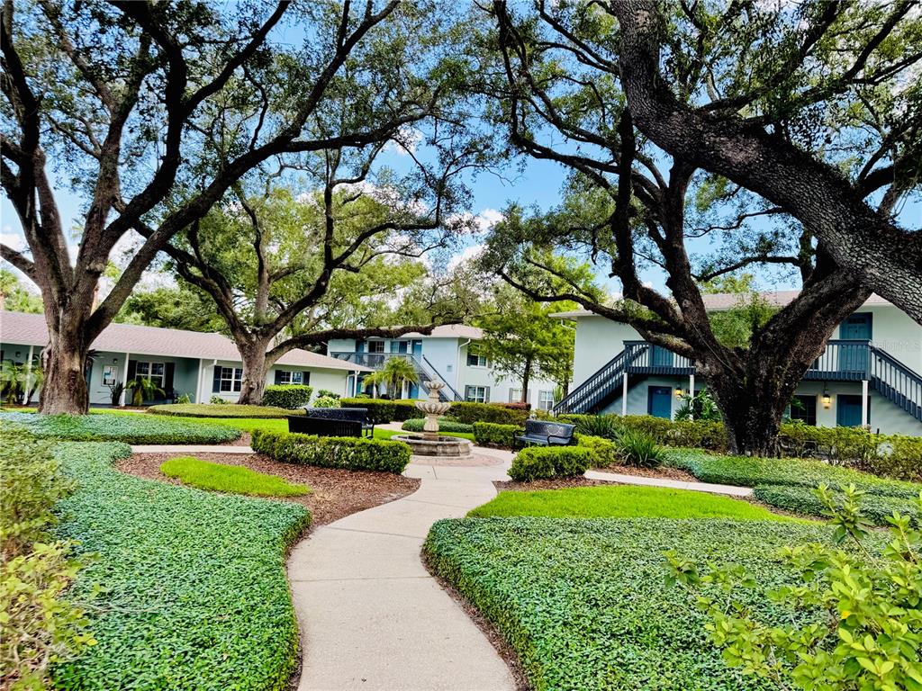 A concrete path leads to a central fountain in a courtyard surrounded by apartment buildings — 4876 CONWAY ROAD UNIT 94, ORLANDO, FL