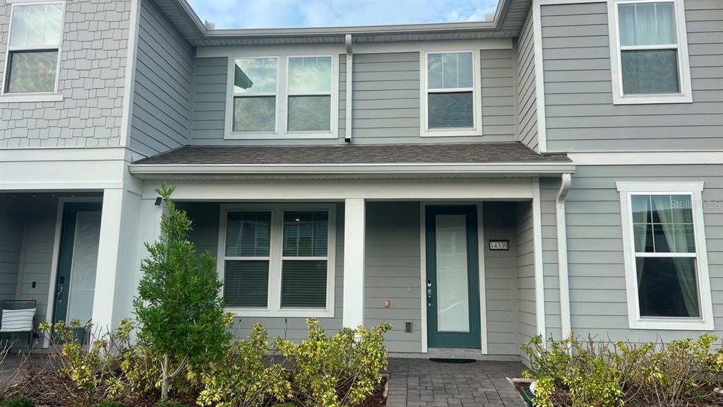 A two-story townhouse exterior features light gray siding, a covered porch, and a green door — 14339 SAPELO BEACH DRIVE, ORLANDO, FL