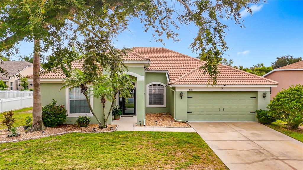 A single-story house with a green exterior, a tiled roof, and a two-car garage — 6161 BOBBY JONES COURT, PALMETTO, FL