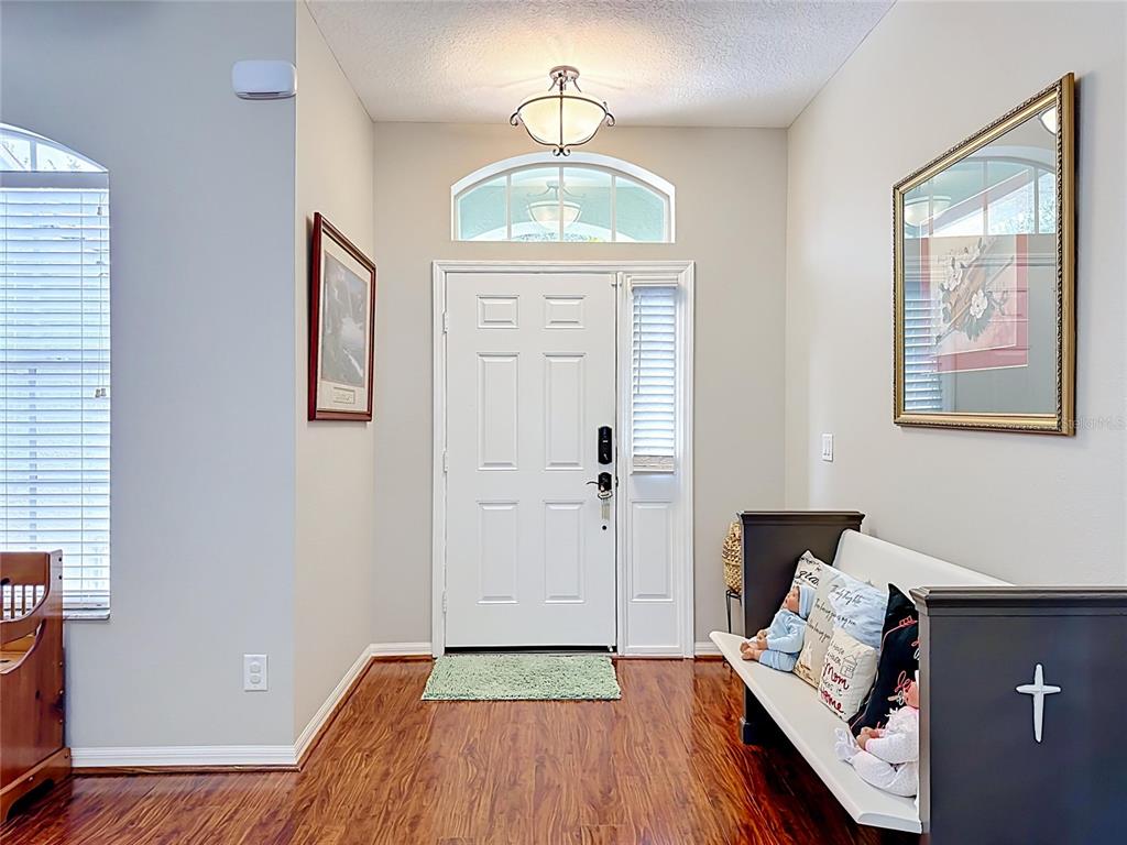 An entryway features wood flooring, a white front door with a sidelight, and a bench — 6161 BOBBY JONES COURT, PALMETTO, FL