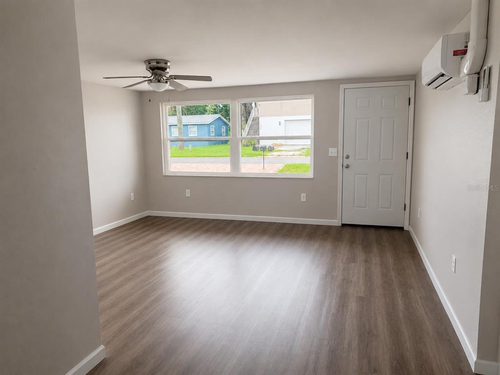 An empty room with light-colored walls, wood-look flooring, a ceiling fan, and a white door — 7335 NEW YORK AVENUE, HUDSON, FL