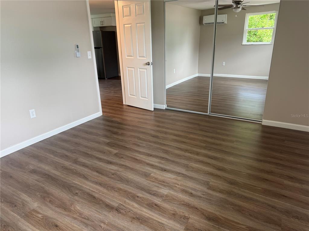 A room with wood-look flooring, a white door, and mirrored closet doors — 7335 NEW YORK AVENUE, HUDSON, FL