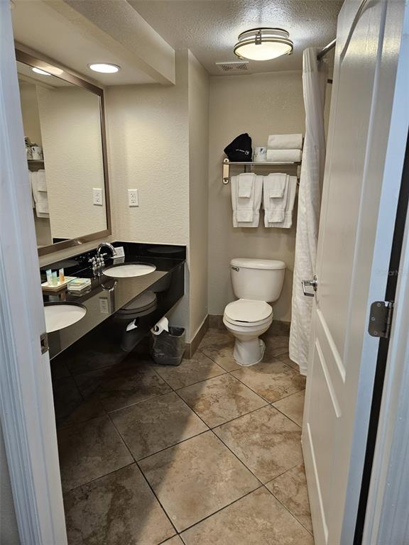 A bathroom features a black vanity countertop, a toilet, and a shower with a white curtain — 3000 MAINGATE LANE UNIT 530, KISSIMMEE, FL