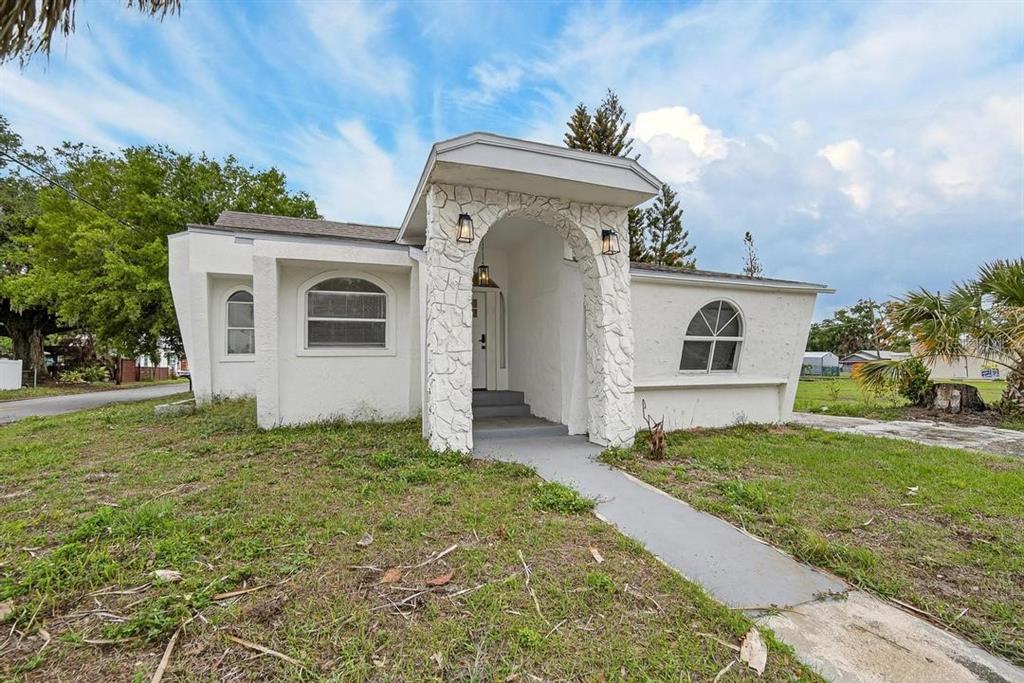 A white house with a stone-accented arched entryway and a concrete walkway — 800 N CHURCH AVENUE, MULBERRY, FL