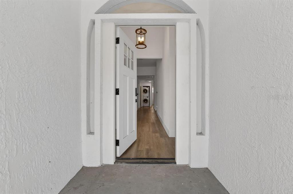An open front door reveals a hallway with wood-look flooring and a hanging light fixture — 800 N CHURCH AVENUE, MULBERRY, FL