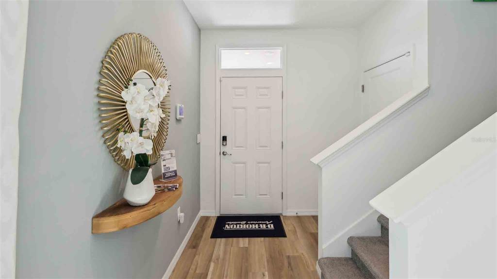 An entryway features a wood-topped floating shelf, a gold sunburst mirror, and a staircase — 10549 TUCKER ROAD, WEEKI WACHEE, FL