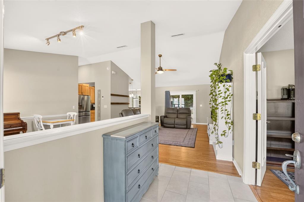 An entryway with a blue dresser leads into an open-concept living room with vaulted ceilings — 6909 SW 80TH DRIVE, GAINESVILLE, FL