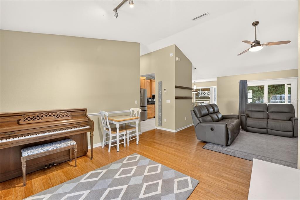 A living room features a piano, a small dining set, and a gray reclining sofa — 6909 SW 80TH DRIVE, GAINESVILLE, FL