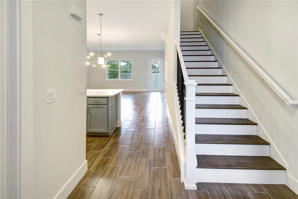 A staircase with dark wood treads and white risers sits beside a kitchen island — 1523 HERITAGE PLACE, OVIEDO, FL