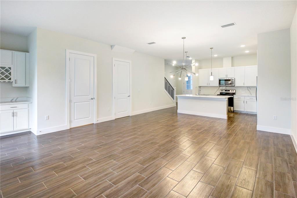 An open-concept kitchen and living area features white cabinetry, a central island, and wood-look flooring — 1523 HERITAGE PLACE, OVIEDO, FL