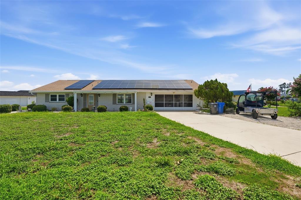 A single-story house with solar panels on the roof and a concrete driveway — 1811 MILFORD CIRCLE, SUN CITY CENTER, FL