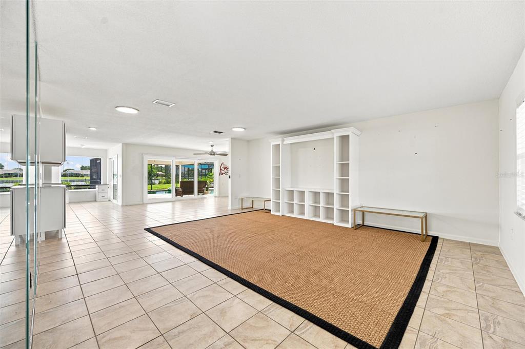 A spacious living room features tile flooring, a large area rug, and a white entertainment unit — 1811 MILFORD CIRCLE, SUN CITY CENTER, FL