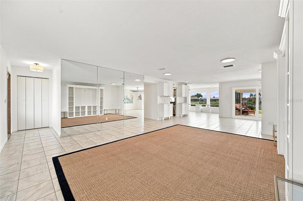 A spacious living area features tiled floors, a large area rug, and a mirrored wall — 1811 MILFORD CIRCLE, SUN CITY CENTER, FL