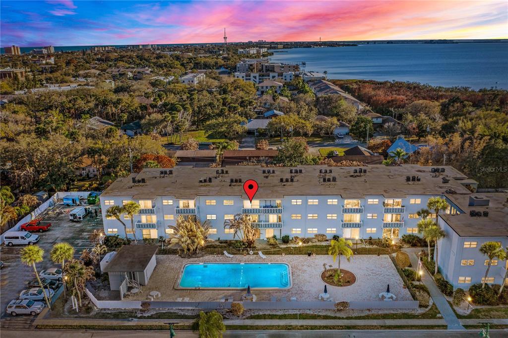 An aerial view shows a multi-story apartment building with a swimming pool in the foreground — 221 COLUMBIA DRIVE UNIT 340, CAPE CANAVERAL, FL