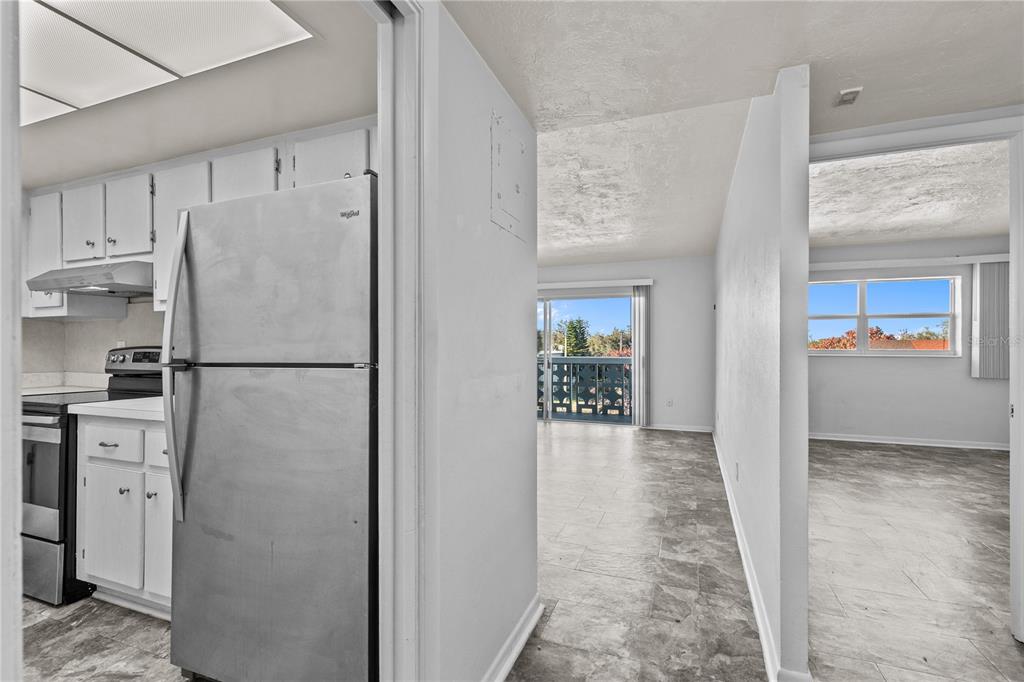 A view from a kitchen into a living area with a balcony and adjacent room — 221 COLUMBIA DRIVE UNIT 340, CAPE CANAVERAL, FL