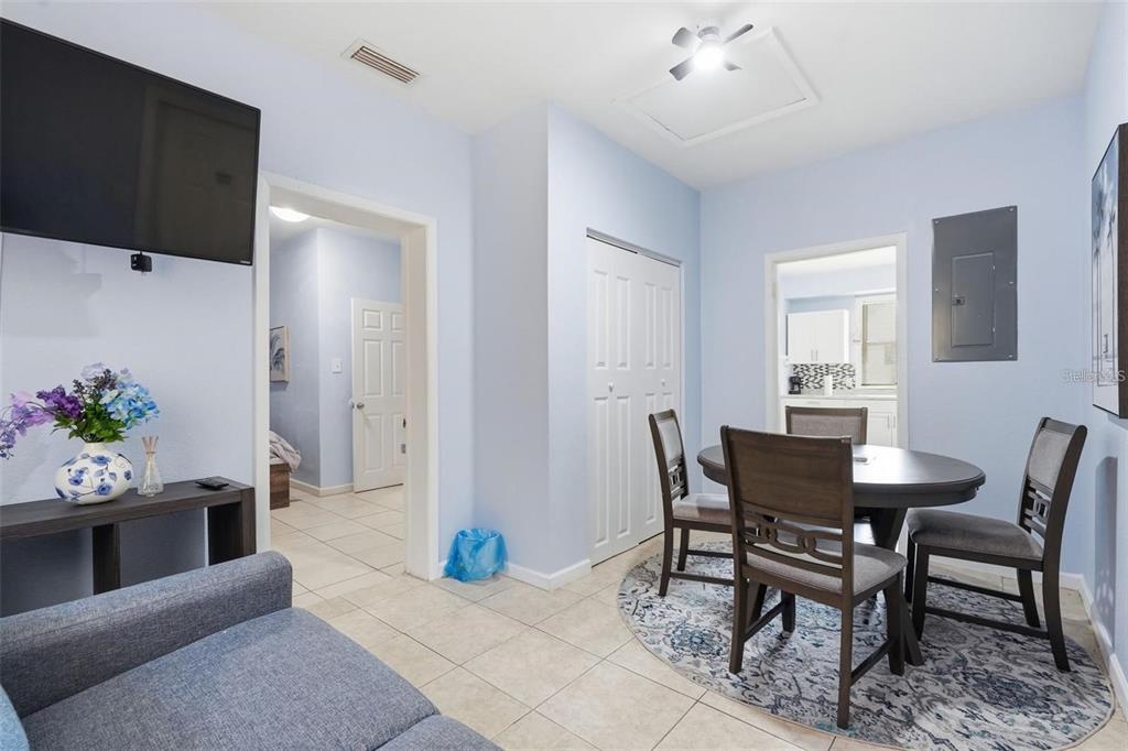 A dining area with a round table and chairs sits next to a living space — 10107 N ASTER AVENUE, TAMPA, FL