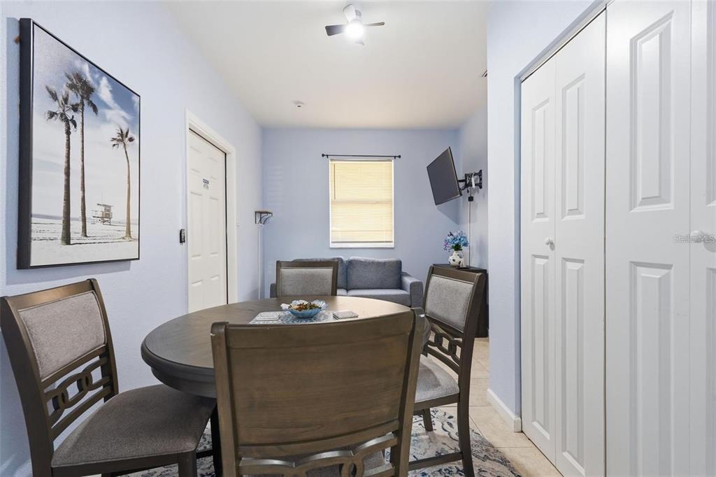 A dining area with a round table and chairs sits in front of a living space — 10107 N ASTER AVENUE, TAMPA, FL