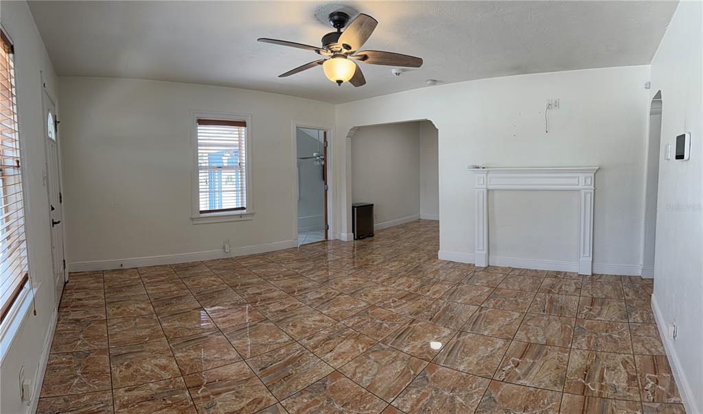 A living room features brown marble-patterned tile flooring, a white fireplace mantel, and a ceiling fan — 702 W PENINSULAR STREET, TAMPA, FL