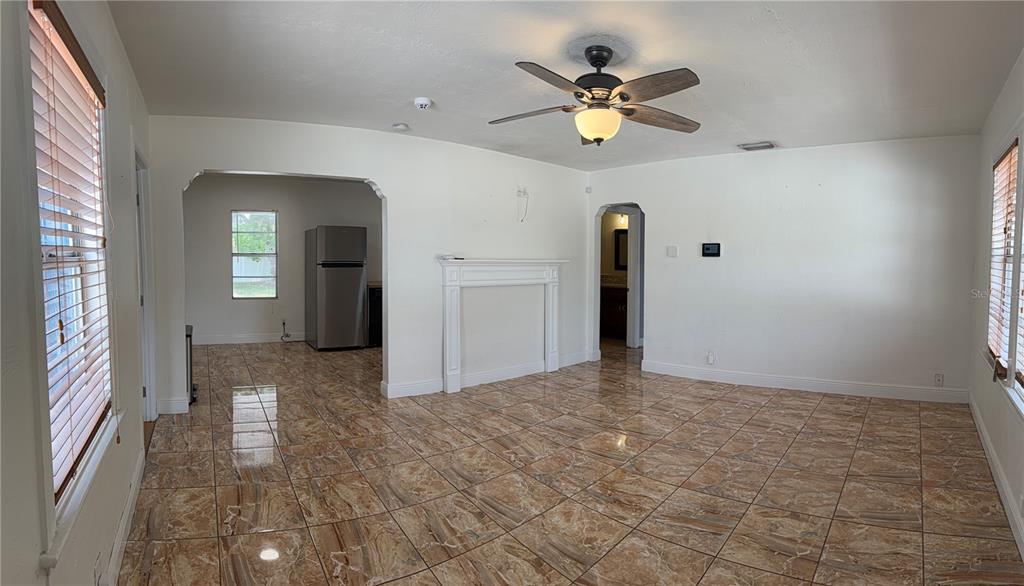 A living room with tan marble-look tile flooring, a white fireplace, and a ceiling fan — 702 W PENINSULAR STREET, TAMPA, FL