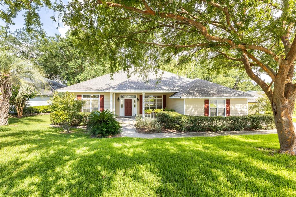A single-story house with tan siding, a red front door, and a large front lawn — 2429 NW 93RD STREET, GAINESVILLE, FL