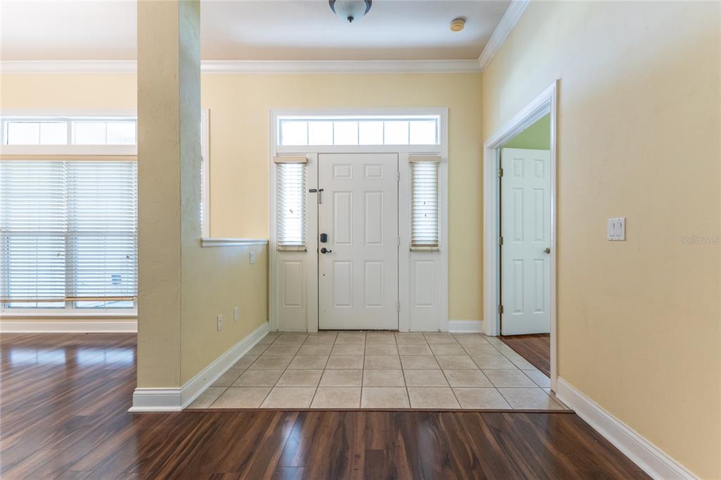 An entryway features a tiled floor, a white front door, and dark wood flooring — 2429 NW 93RD STREET, GAINESVILLE, FL