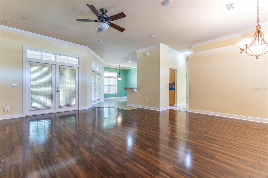 A spacious living area features dark wood flooring, a ceiling fan, and glass patio doors — 2429 NW 93RD STREET, GAINESVILLE, FL
