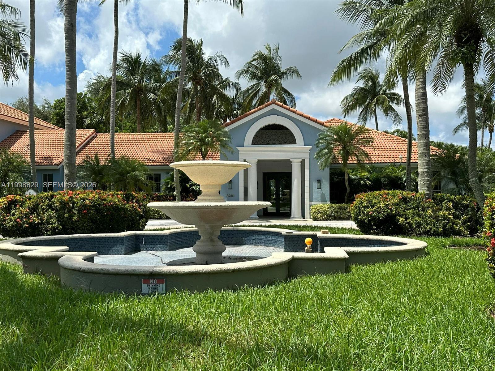 A stone fountain sits in front of a blue building with a tiled roof — 3113 Clint Moore Rd # 103, Boca Raton FL 33496, BOCA RATON, FL