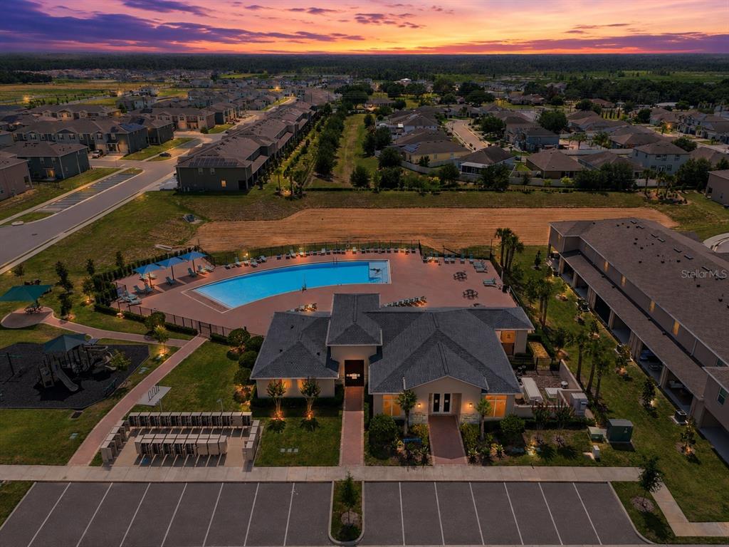 An aerial view shows a community clubhouse with a swimming pool and adjacent parking lot — 1767 WOODEN STREET, DAVENPORT, FL
