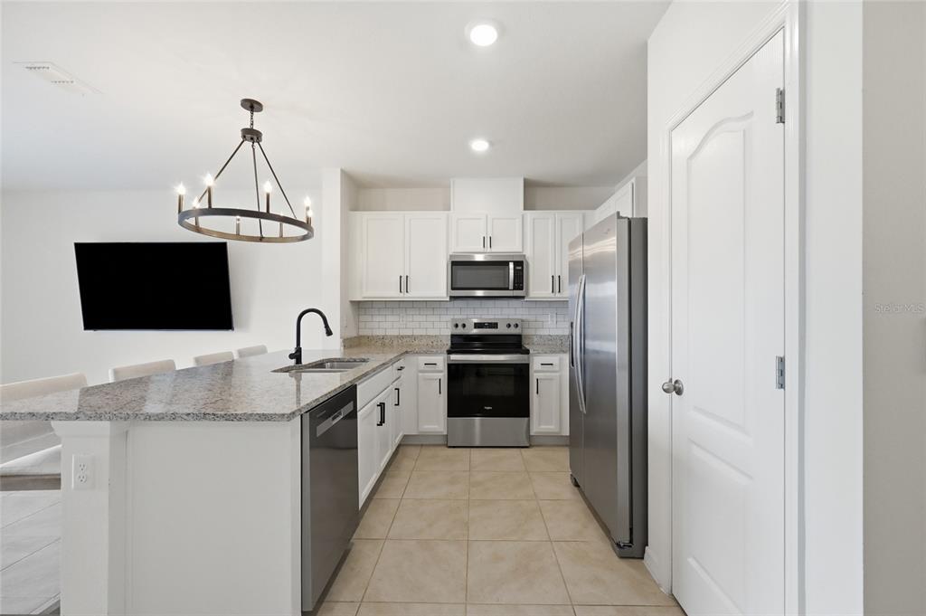A kitchen features white cabinets, granite countertops, stainless steel appliances, and a large island — 1767 WOODEN STREET, DAVENPORT, FL