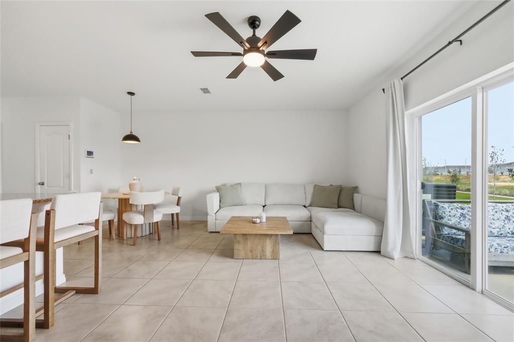 An open-concept living and dining area features tile floors, a sectional sofa, and sliding doors — 1767 WOODEN STREET, DAVENPORT, FL