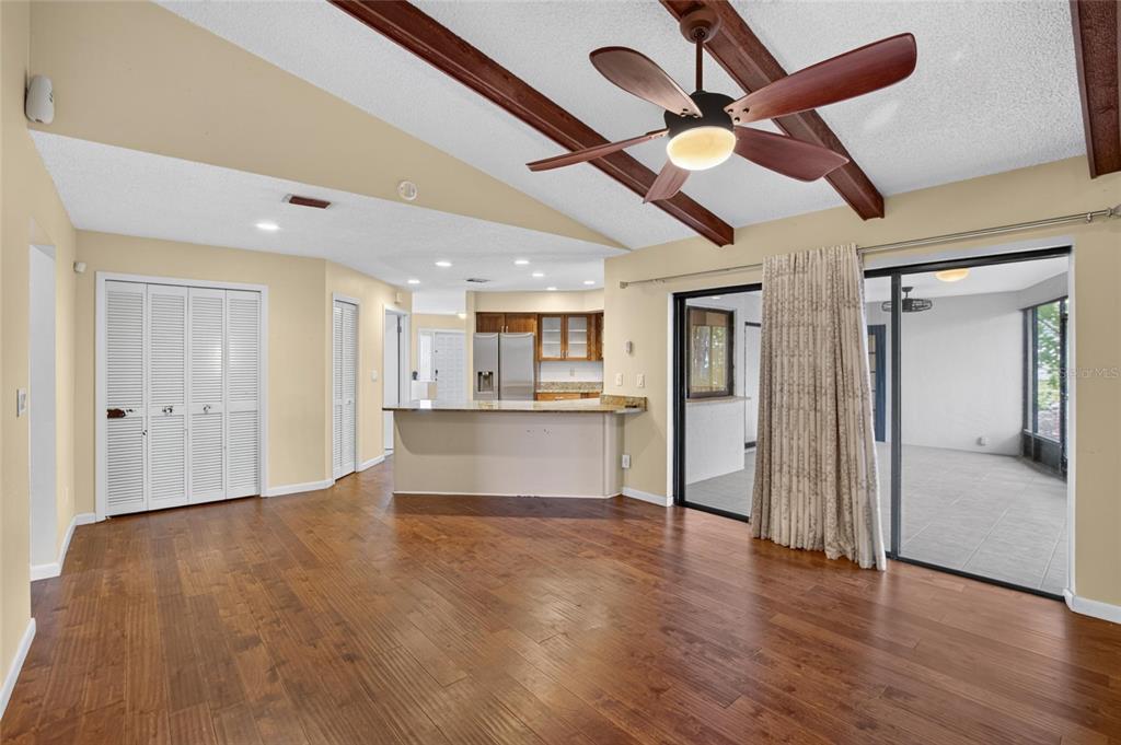 A living room with wood flooring, a vaulted ceiling with beams, and a kitchen pass-through — 1201 SANDALWOOD DRIVE, PLANT CITY, FL