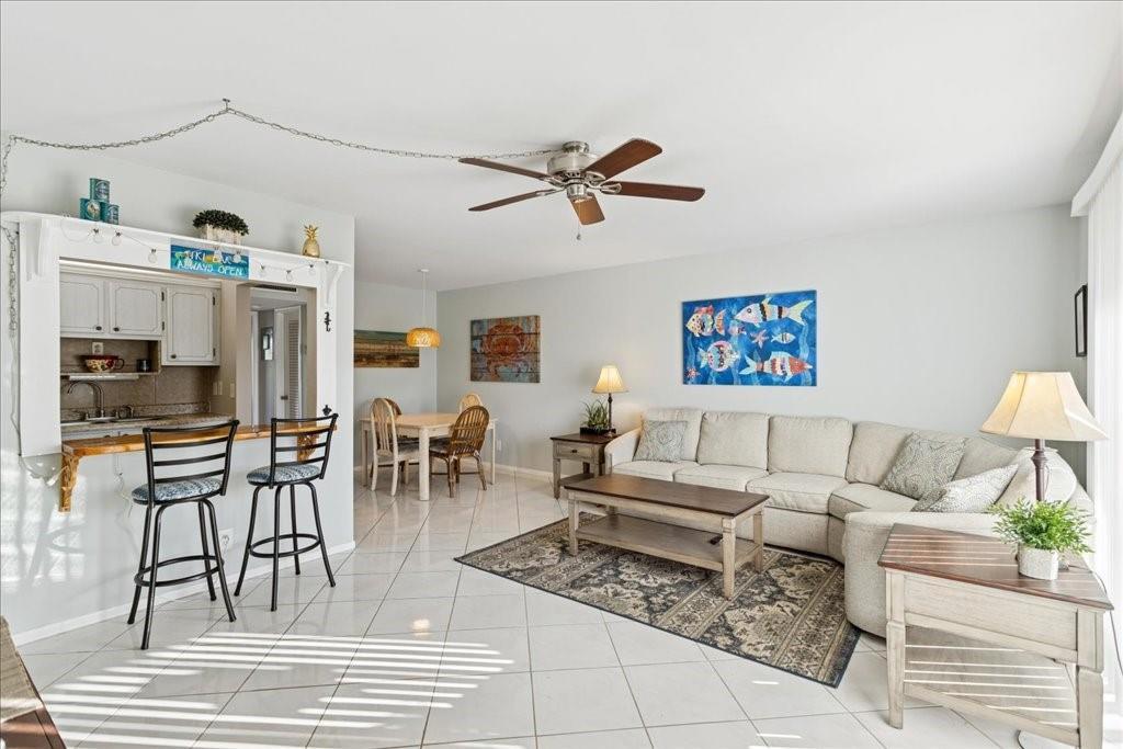 An open-concept living and dining area features tile flooring, a breakfast bar, and coastal decor — 95 North Boulevard # 2b, Boynton Beach FL 33435, BOYNTON BEACH, FL
