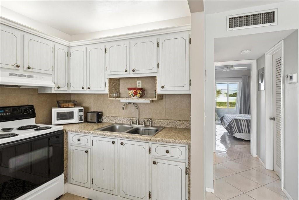 A kitchen with white cabinets, granite countertops, and a view into a bedroom — 95 North Boulevard # 2b, Boynton Beach FL 33435, BOYNTON BEACH, FL