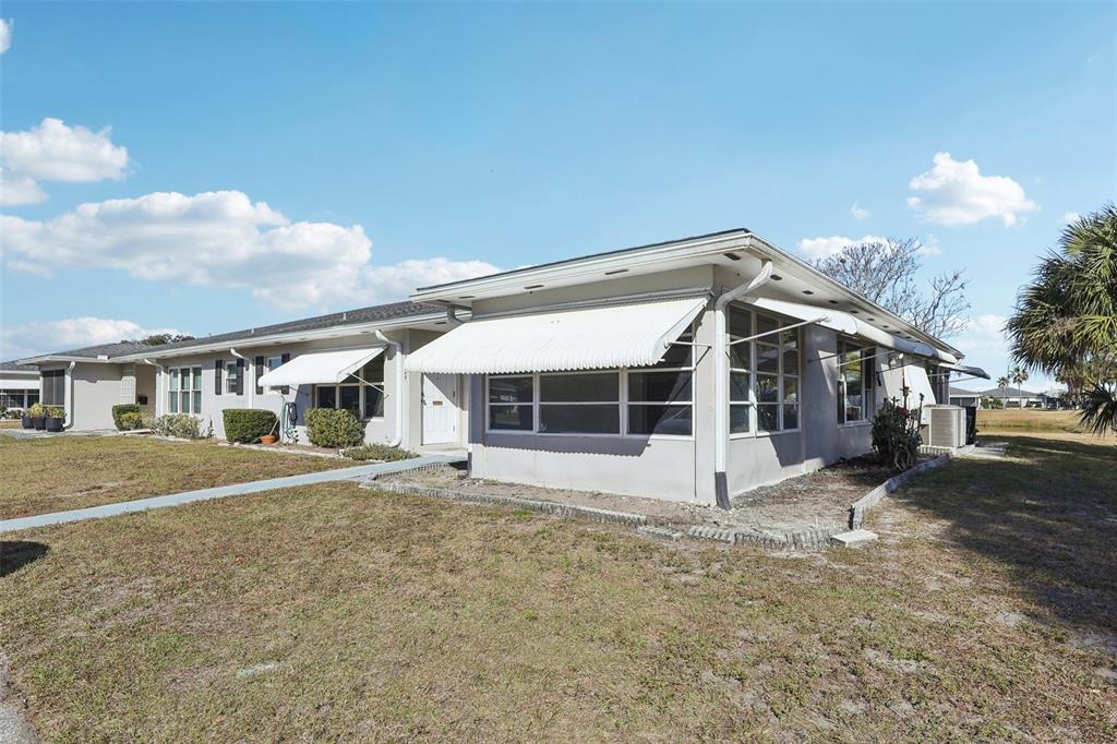 A single-story house with white siding, metal awnings, and a flat roof under a blue sky — 11147 ACME DRIVE UNIT D, ORLANDO, FL